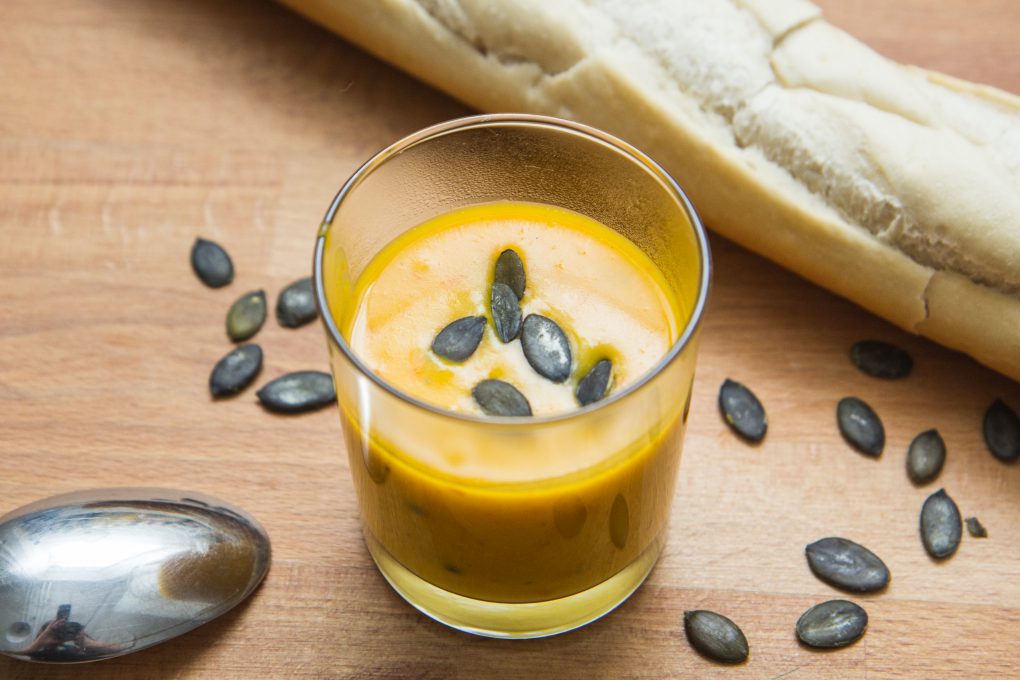 pumpkin soup in a cup decorated with pumpkin seeds