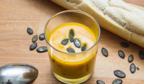 pumpkin soup in a cup decorated with pumpkin seeds
